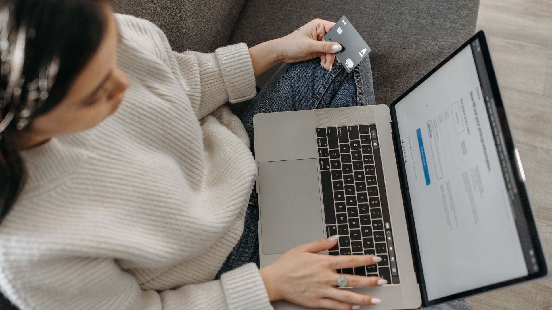 A woman using a laptop while holding a payment card