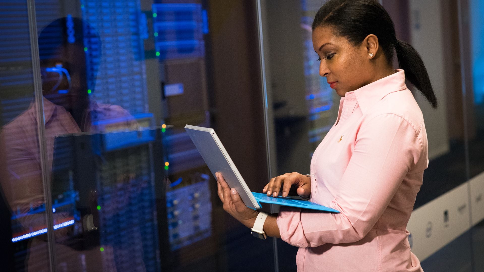 A technology worker using a laptop beside server cabinets