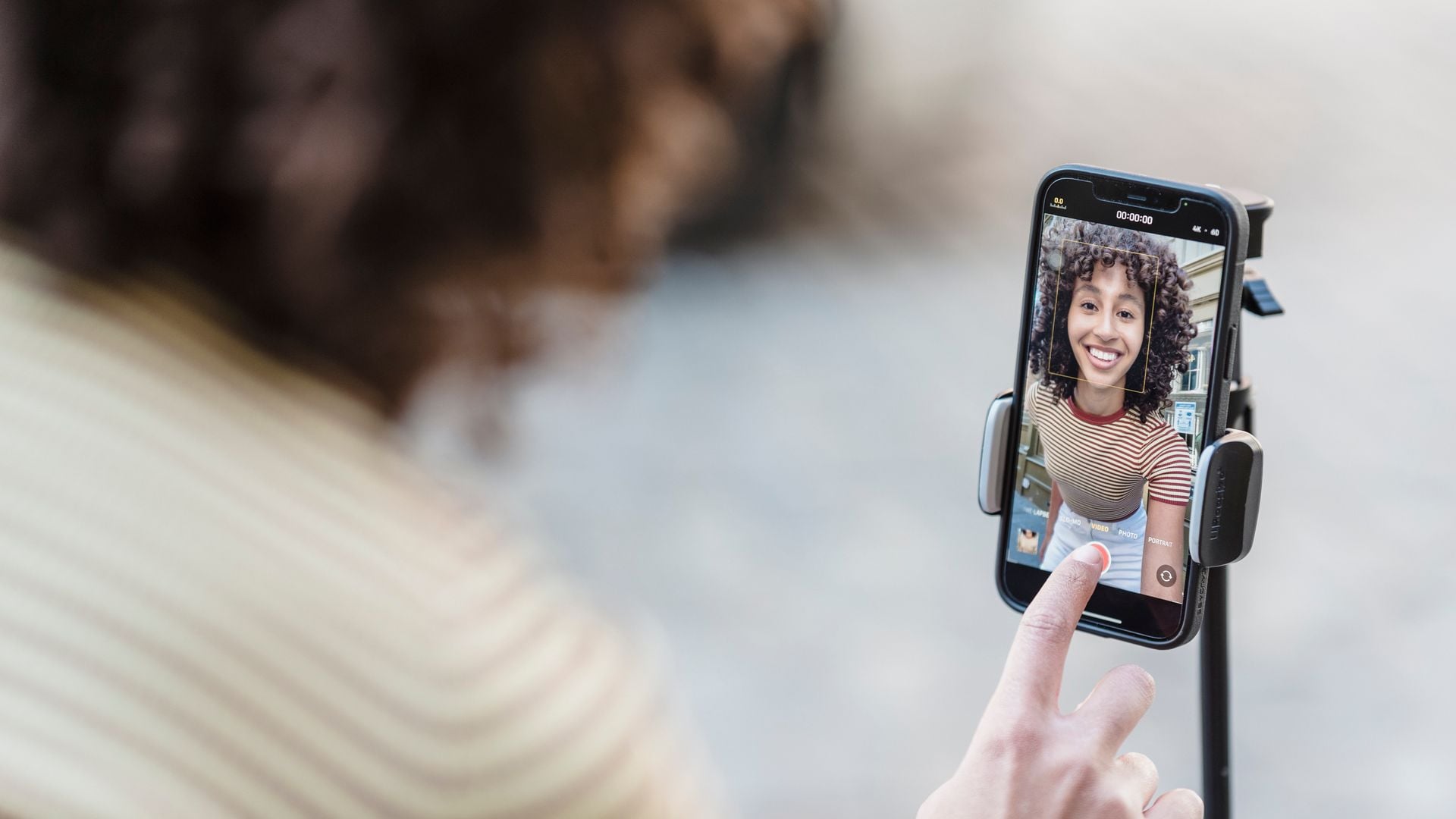 A creator prepares to record a video using a smartphone on a mount.