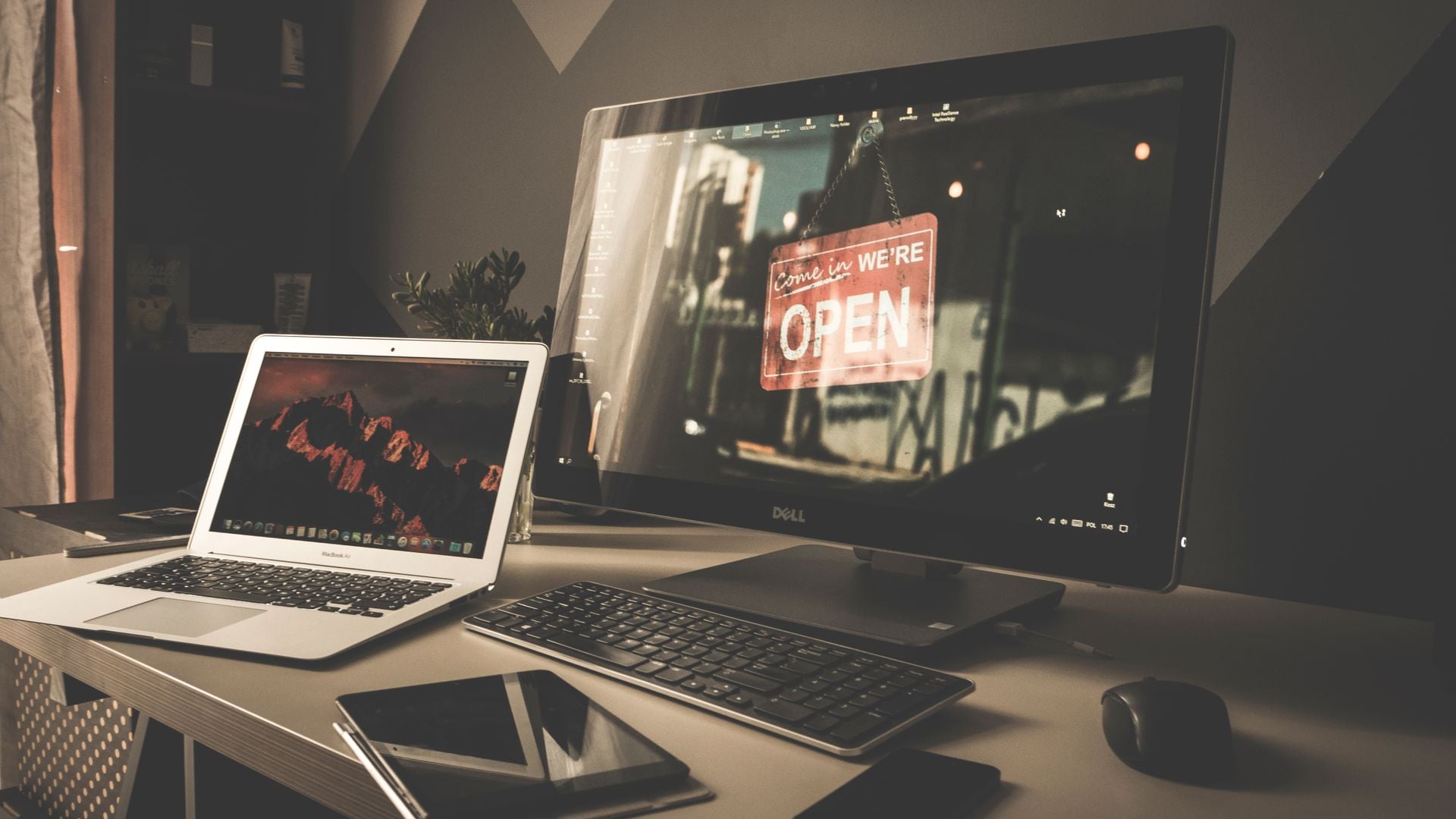 A laptop, desktop monitor and tablet sit on an office desk.