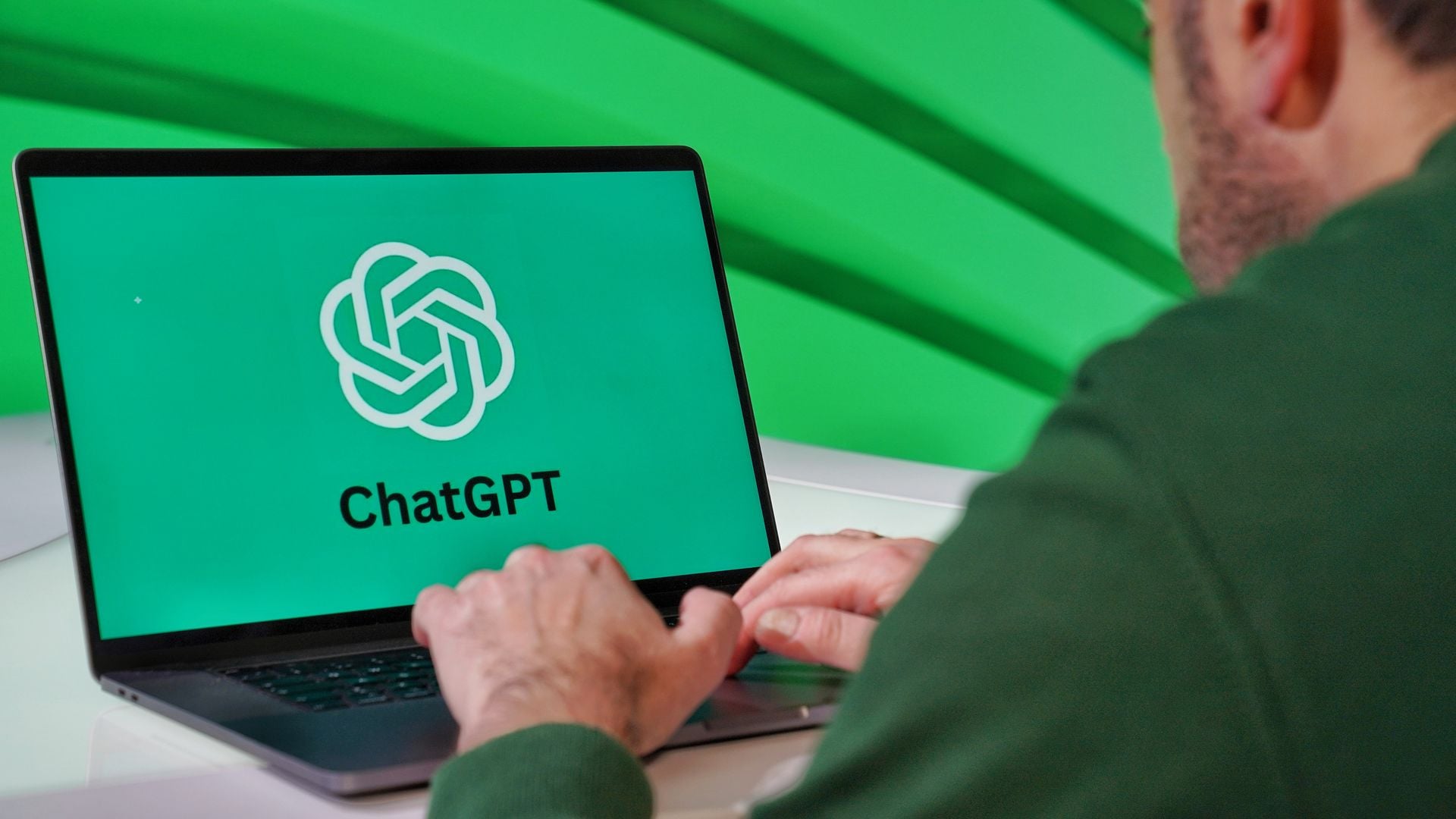 Person at a laptop displaying the ChatGPT logo against a green background