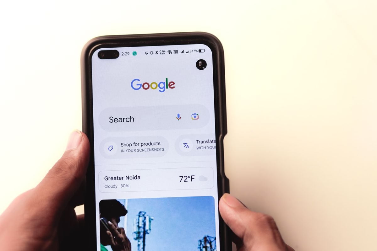 Hands holding a smartphone with a Google search screen