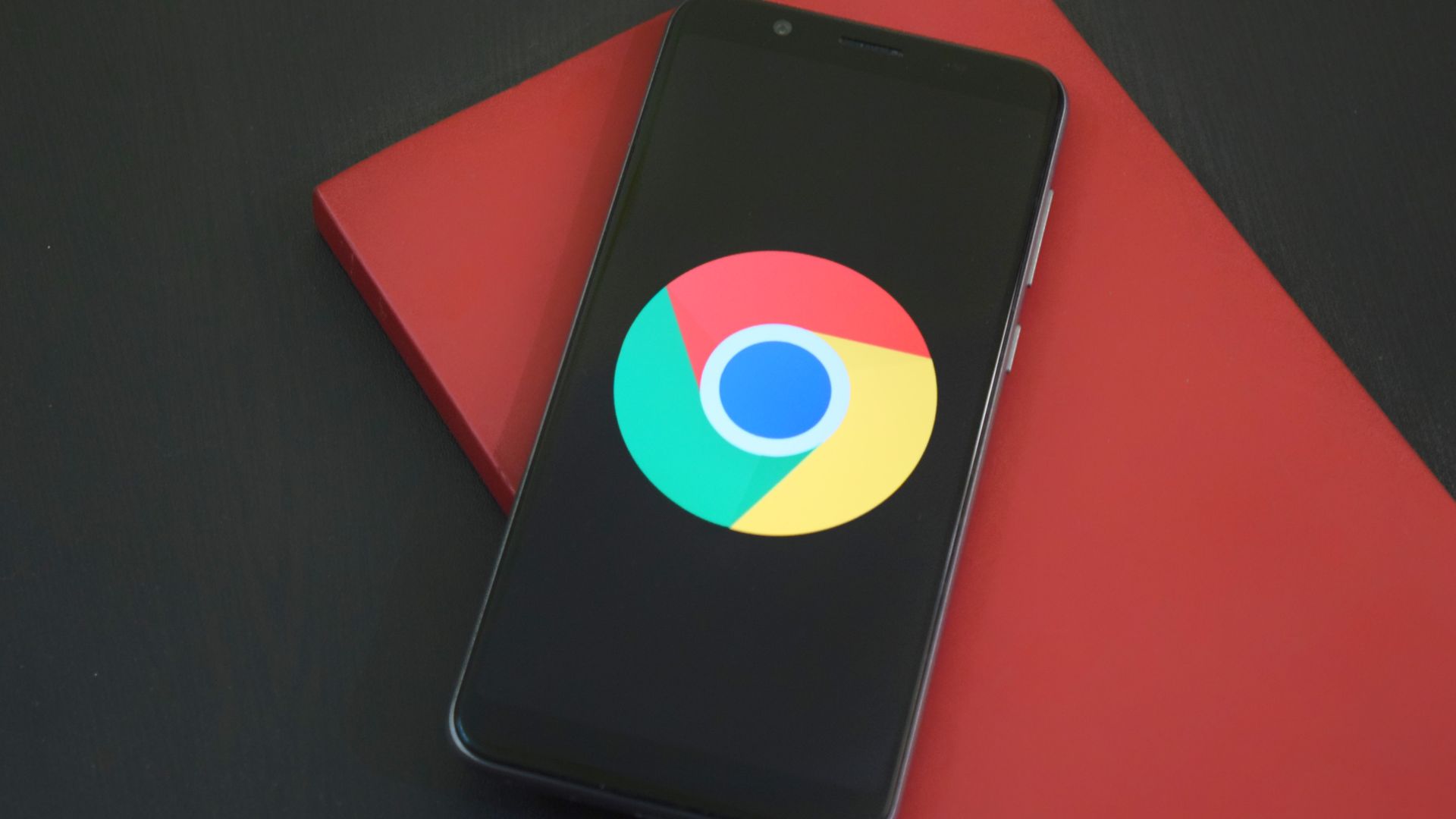 Chrome logo displayed on a smartphone resting on a red notebook