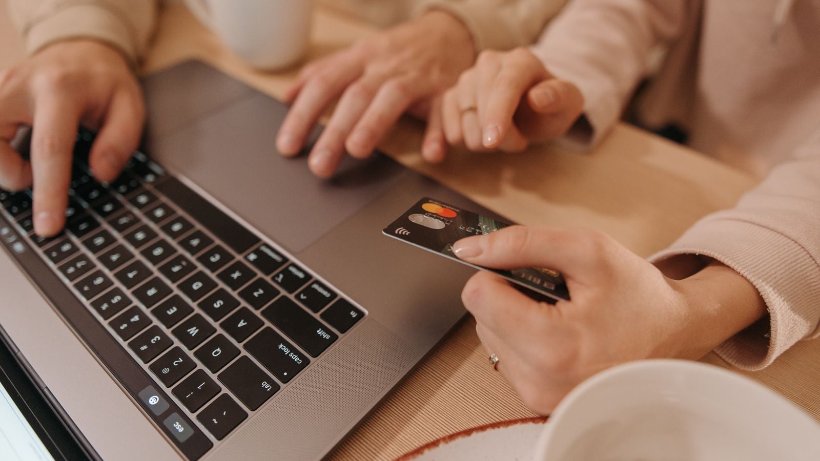 Hands using a laptop and payment card for an online purchase