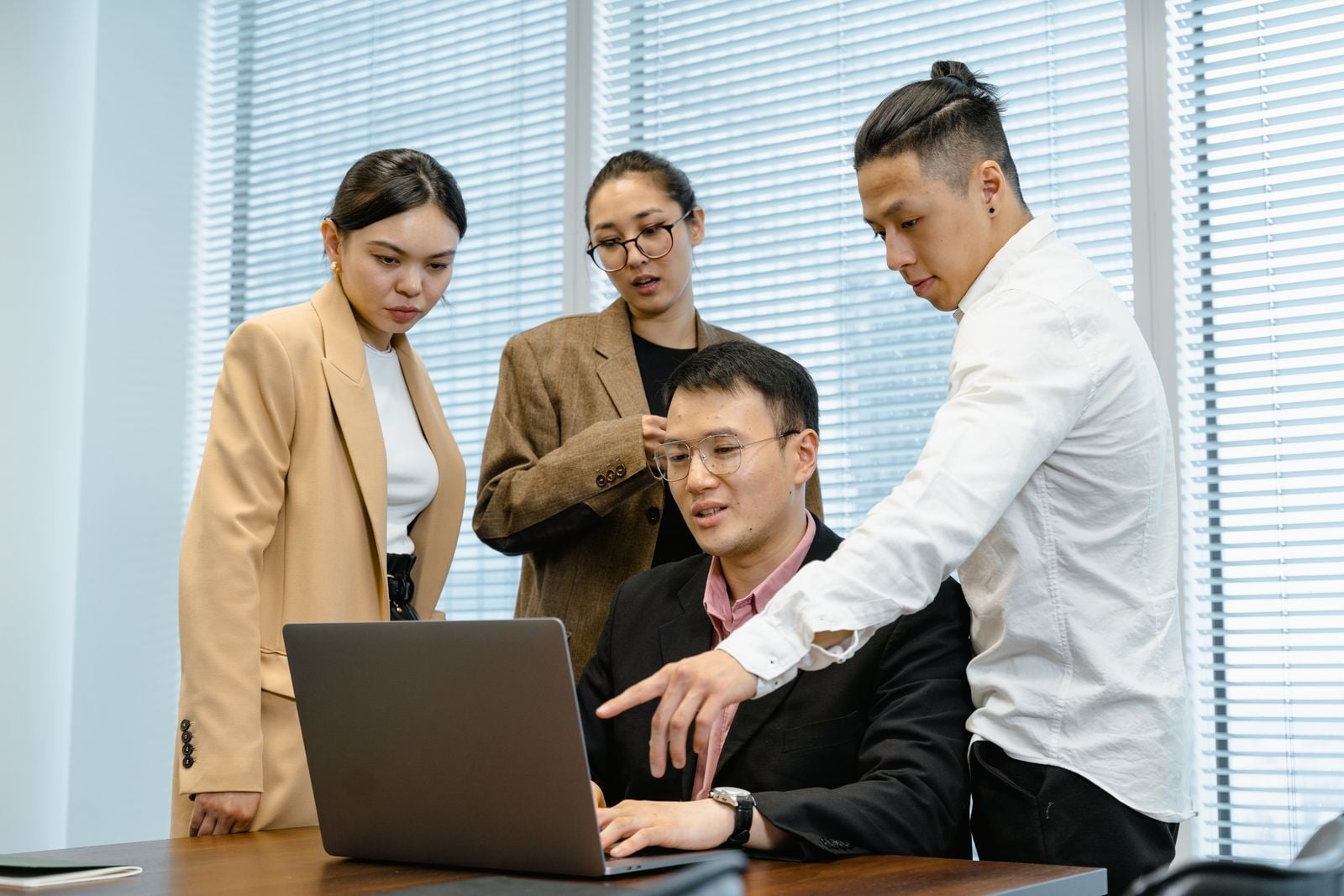 Colleagues gathered around a laptop in an office