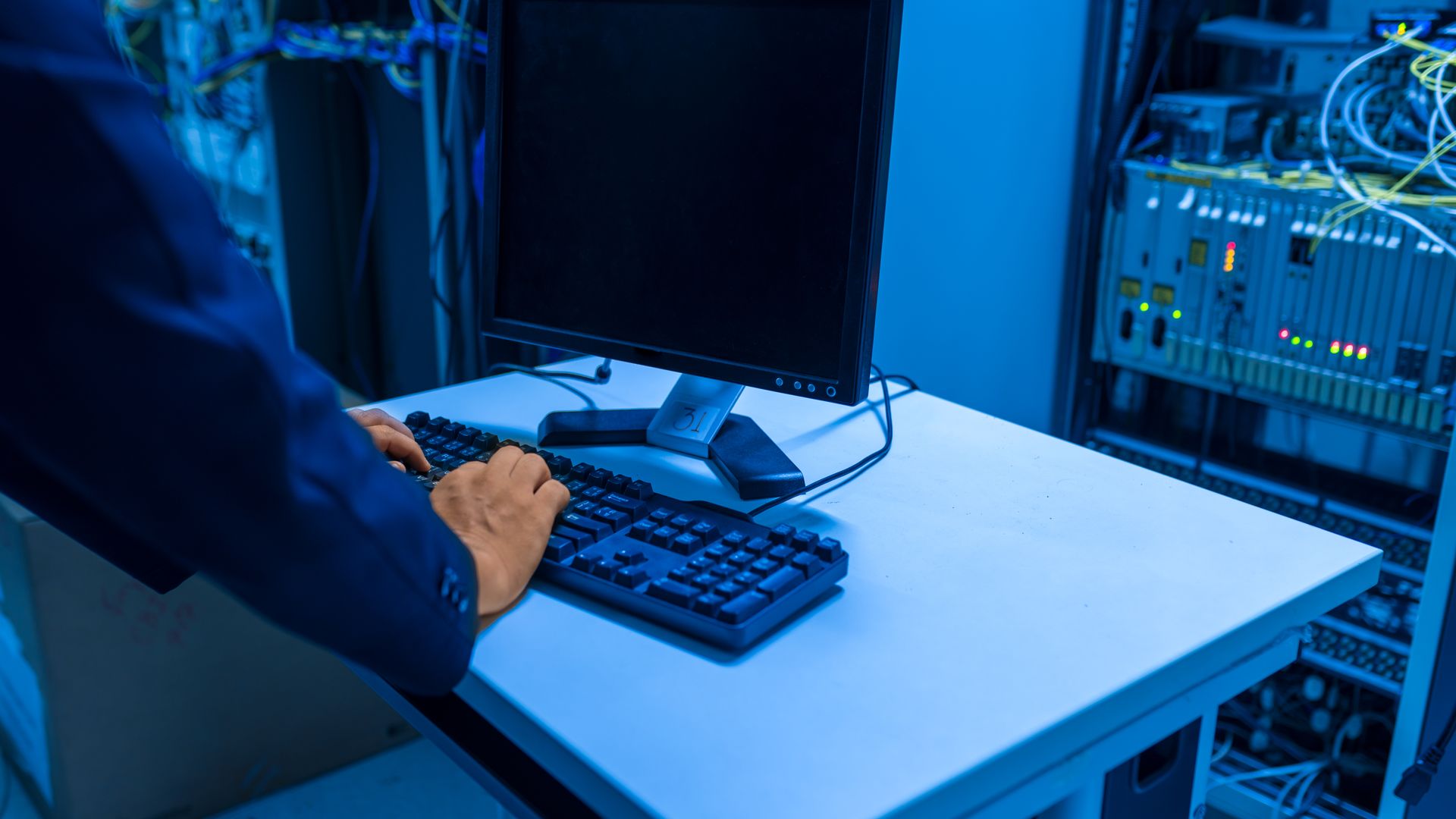 Technician using a computer beside server racks
