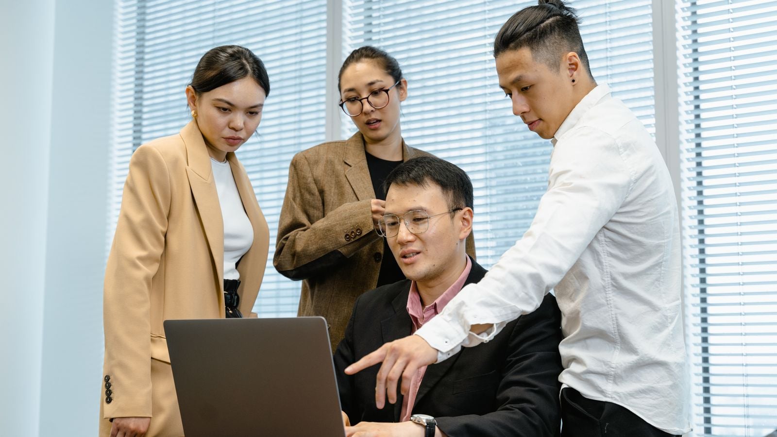 Four colleagues reviewing a laptop screen together