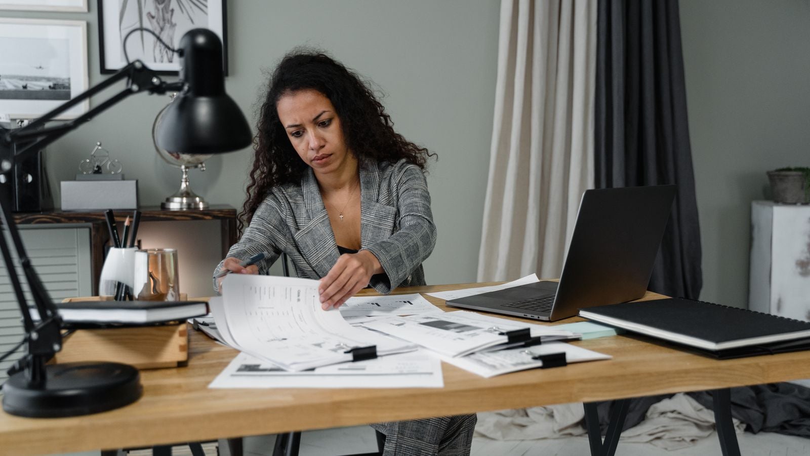 Woman reviewing papers at a desk beside a laptop