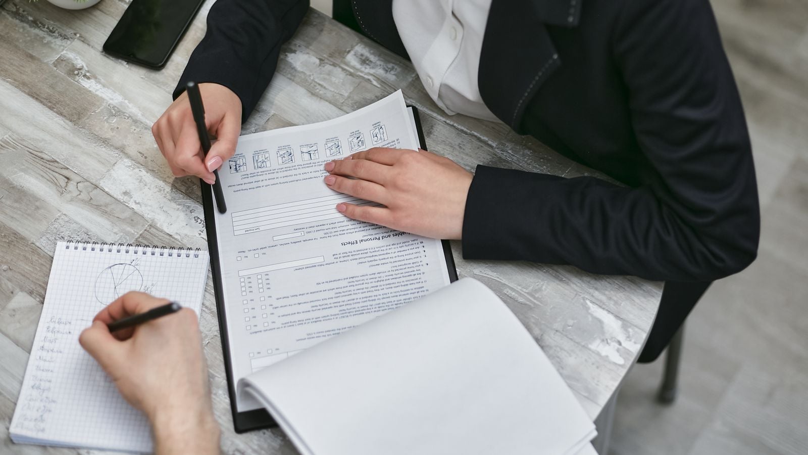 Two colleagues reviewing documents and taking notes