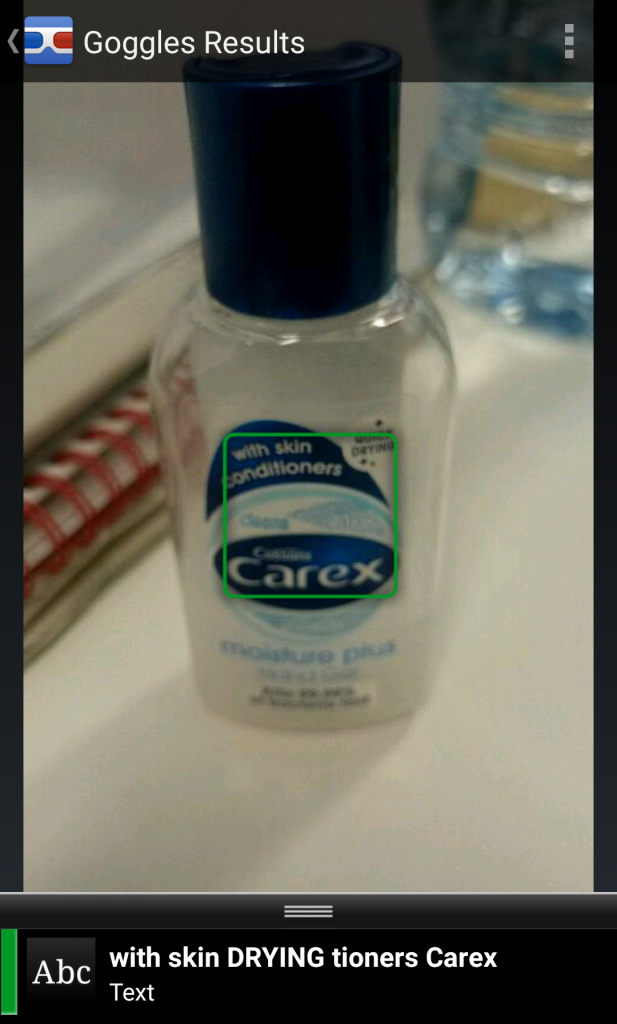 A mobile screenshot of a Google Goggles search. The screen shows a small bottle of Carex antibacterial hand gel with skin conditioners. A green square surrounds the product label, and a text string at the bottom of the screen reads: with skin DRYING tioners Carex