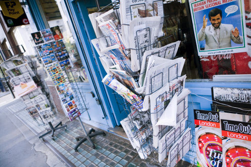 International broadsheet newspapers and postcards on wire racks outside news agent's shop