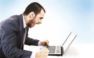 An angry man shouting at a laptop