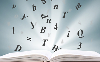 A dictionary with letters flying above it